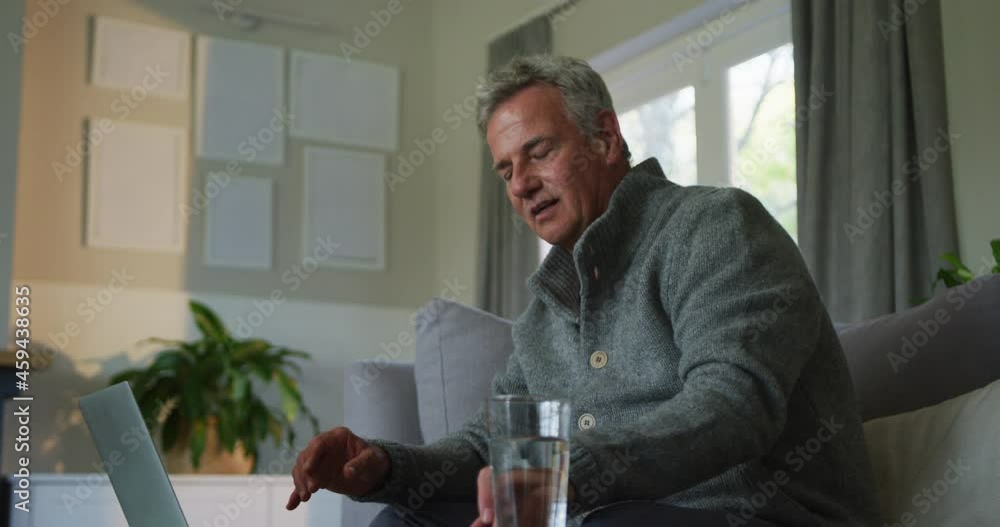 Animation of caucasian senior man doing paperwork and using laptop at home Animation of caucasian senior man doing paperwork and using laptop at home
