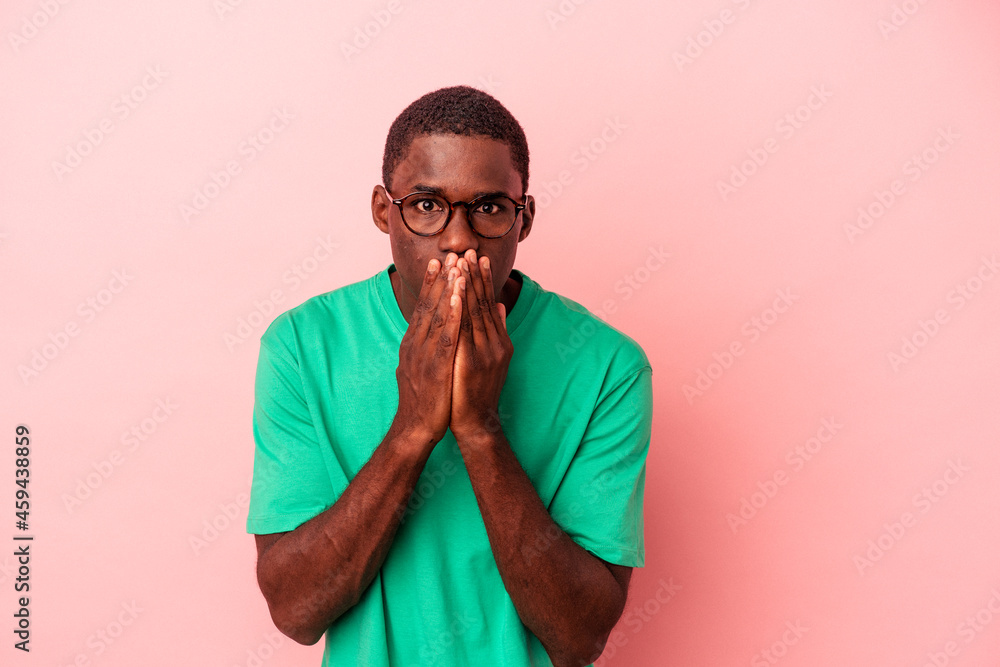 Young African American man isolated on pink background shocked covering mouth with hands. Young African American man isolated on pink background shocked covering mouth with hands.
