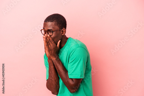 Young African American man isolated on pink background laughing about something, covering mouth with hands.