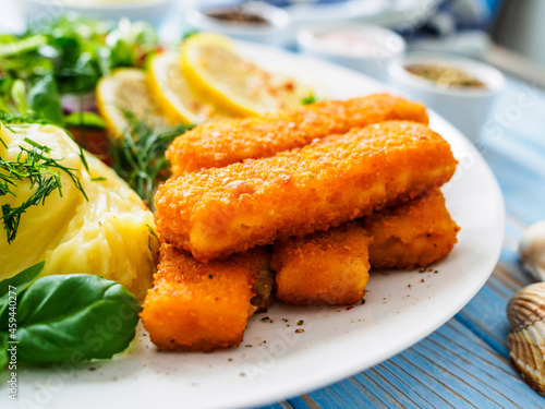 Canvas Print Fried fish sticks with potato puree and fresh vegetable salad on wooden table