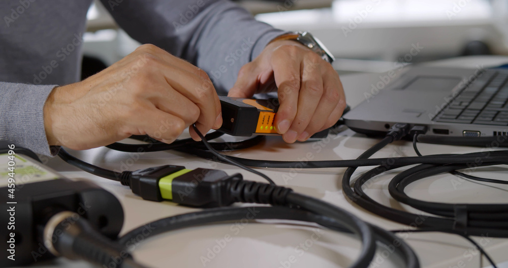 Cropped shot of male it-specialist connect wires to gadget and fix laptop