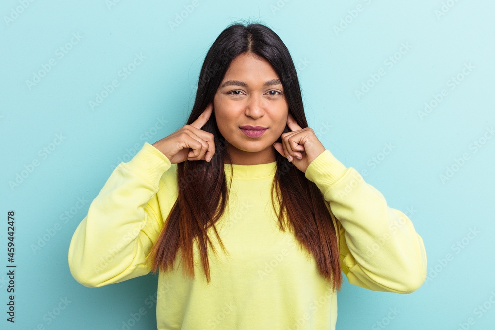 Young Venezuelan woman isolated on blue background covering ears with fingers, stressed and desperate by a loudly ambient. Young Venezuelan woman isolated on blue background covering ears with fingers, stressed and desperate by a loudly ambient.