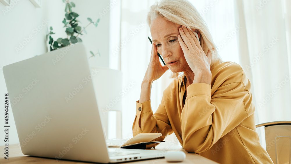 Handsome mid aged woman at her bright and sunny apartment. Tired of computer with headache Handsome mid aged woman at her bright and sunny apartment. Tired of computer with headache