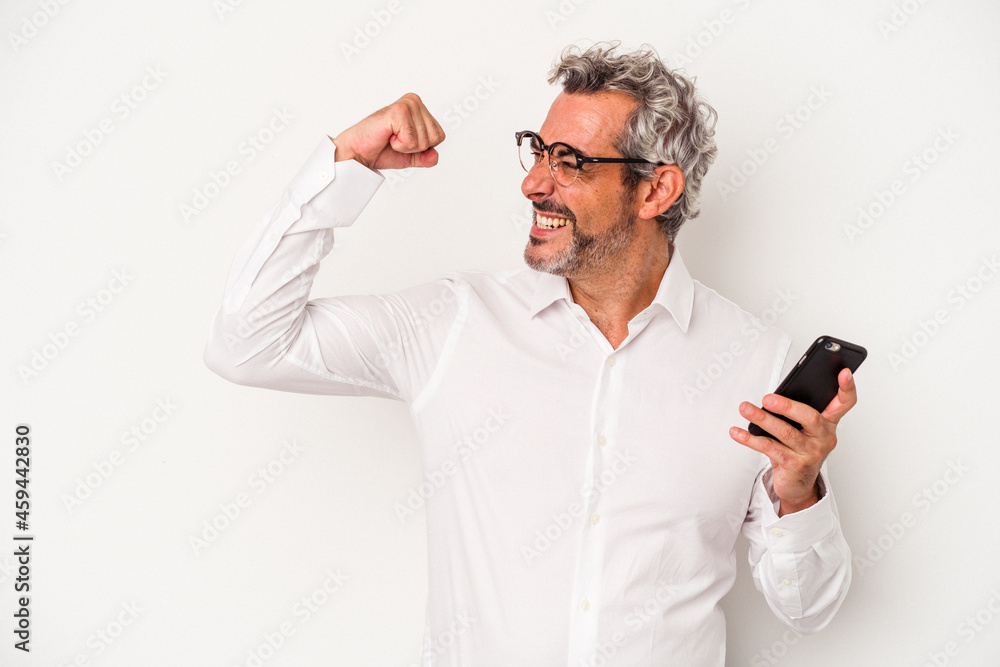 Middle age caucasian business man holding a mobile phone isolated on white background raising fist after a victory, winner concept. Middle age caucasian business man holding a mobile phone isolated on white background raising fist after a victory, winner concept.