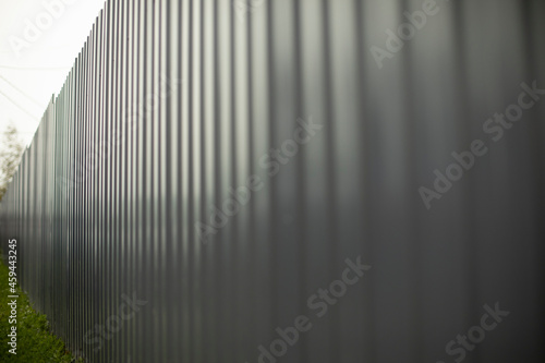 Grey fence made of metal. Solid high fence. Profiled metal is used in the fence of private territory.