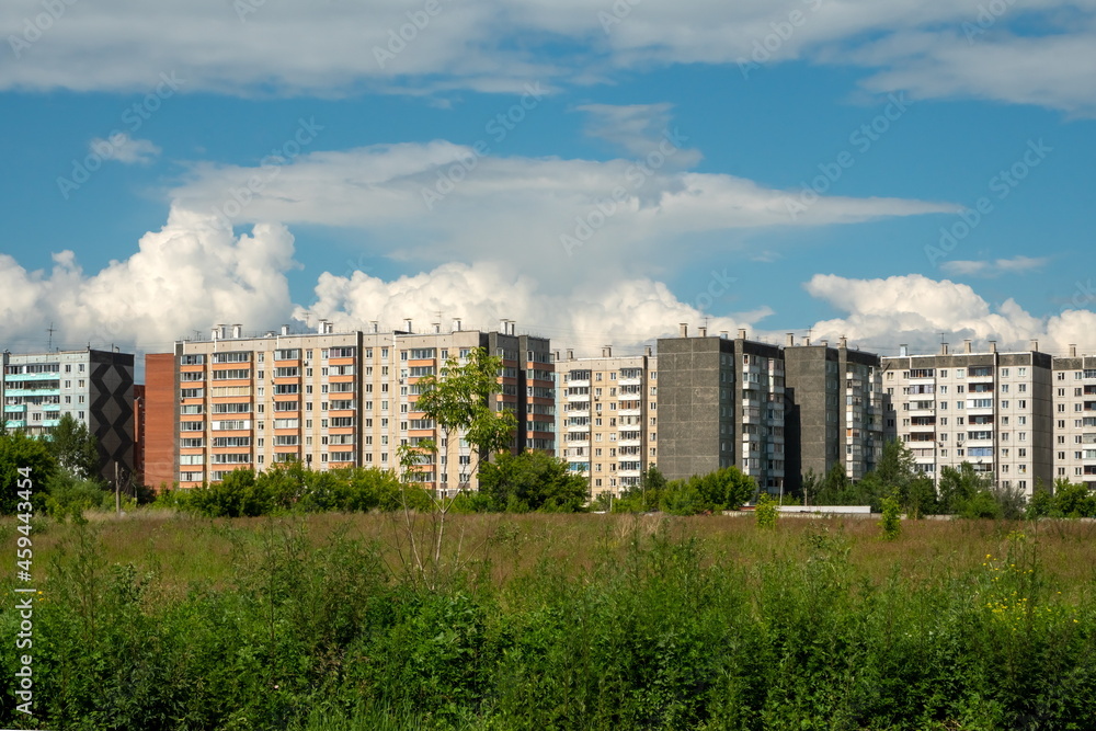 View of typical residential apartment buildings and the vacant lot in front of them on a sunny summer day.