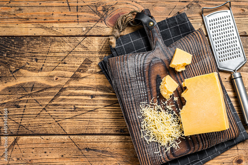 Grated cheddar cheese piece on a wooden board. Wooden background. Top view. Copy space