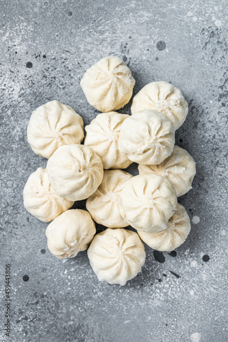 Frozen uncooked baozi dumplings stuffed with meat. Gray background. Top view