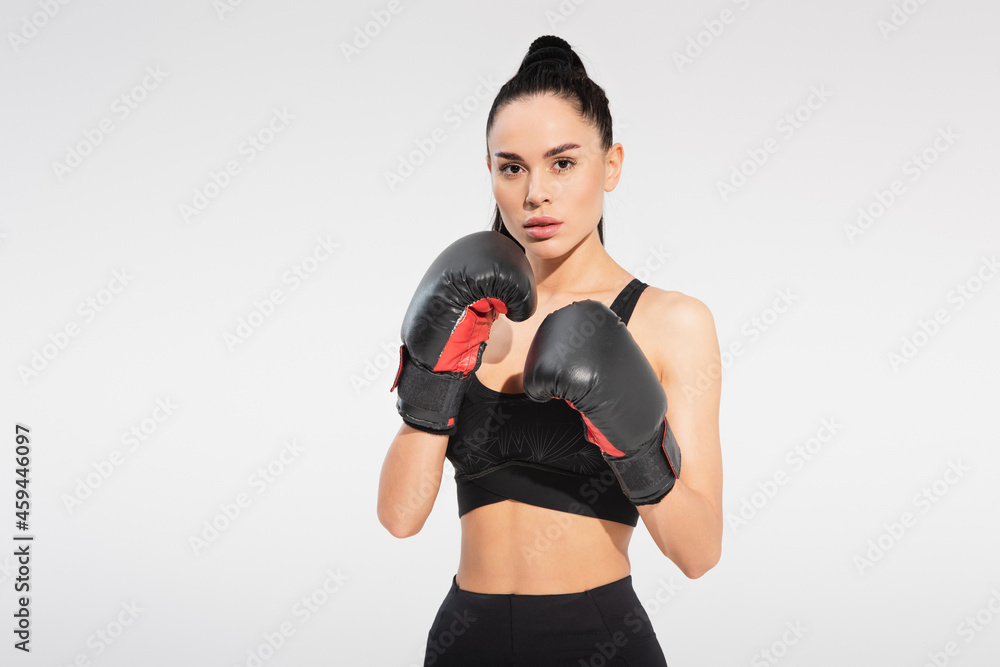 strong young sportswoman in boxing gloves isolated on grey