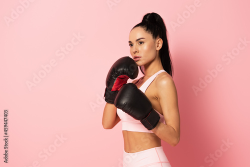 Bild auf Leinwand strong woman in sportswear and boxing gloves on pink