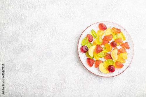 Various fruit candies on plate on gray concrete background. copy space, top view.