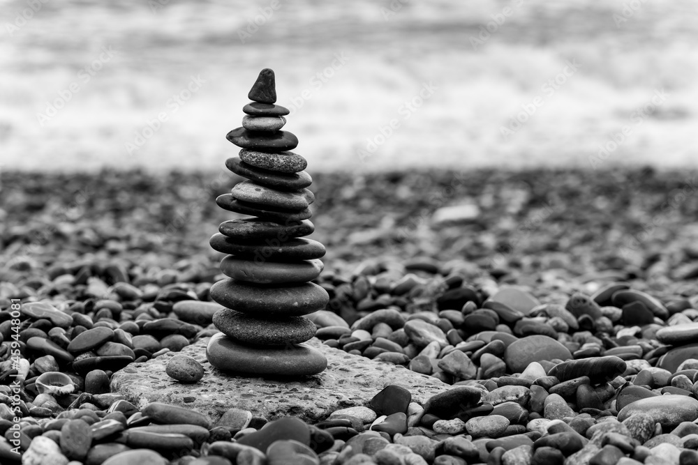 Obraz premium Pyramid of pebbles on the beach.Waves in background, black and white