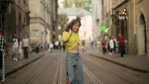Outdoor summer lifestyle video of young pretty hipster woman having fun, listening music and dancing on the street, city center Europe, fun ,joy, emotions