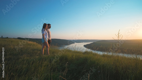 The romantic couple standing on a mountain top on a beautiful river background © DK