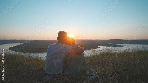 The romantic couple sitting on a mountain top on a beautiful sunset background