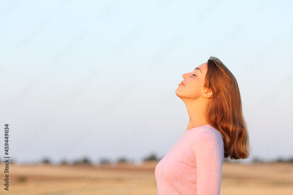 Woman breathing fresh air at sunrise in a field
