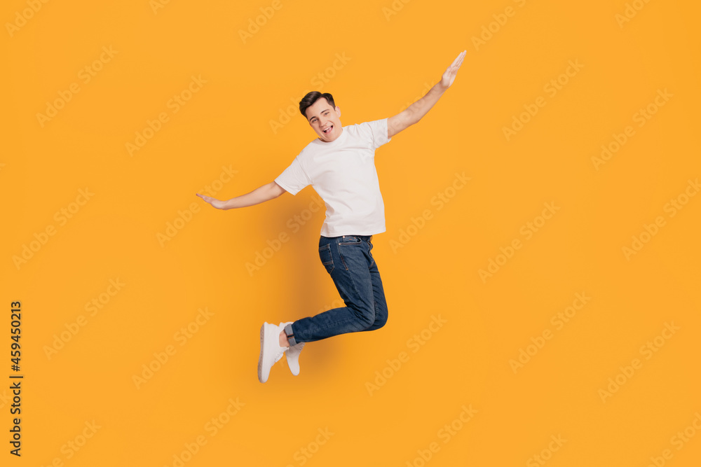 Portrait of crazy inspired guy jump make plan figure hands wings on yellow background