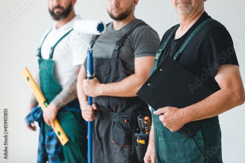 Crew of three professional builder wearing overalls standing in empty interior photo