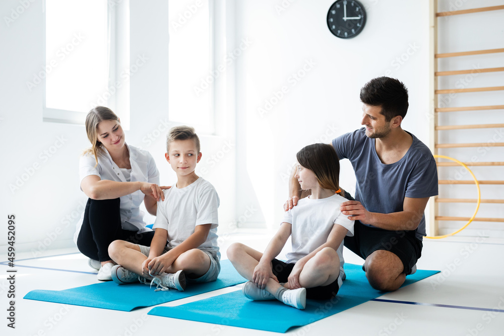 Kids sitting on blue yoga mats with their professional physician Kids sitting on blue yoga mats with their professional physician