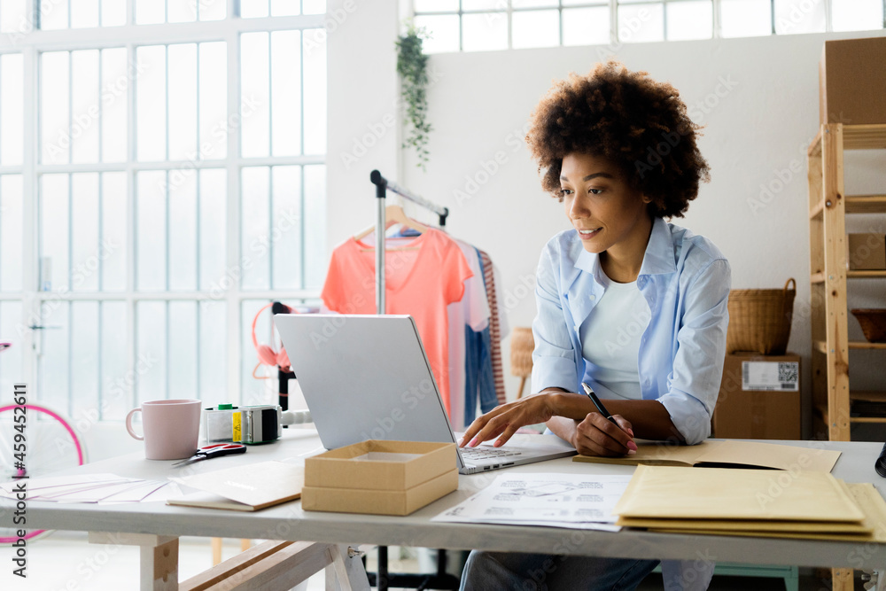 Female fashion designer working on laptop in studio Female fashion designer working on laptop in studio