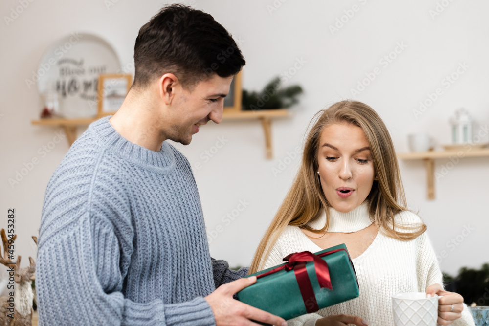 Sweet couple opening Christmas gifts in the living room at home Sweet couple opening Christmas gifts in the living room at home