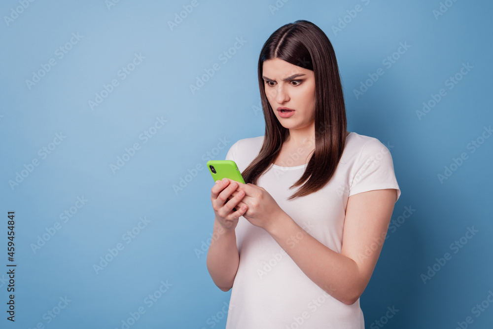 Portrait of speechless shocked lady hold phone look screen read post on blue background Portrait of speechless shocked lady hold phone look screen read post on blue background