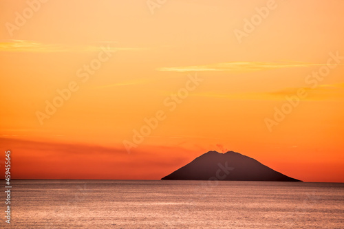 Stromboli active volcano against colorful sunset in Italy, view from Calabria coast.