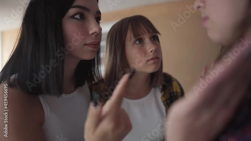 Angry bullies threatening fighting with unrecognizable teenage girl. Portrait of aggressive Caucasian classmates discriminating groupmate. Antisocial behavior and aggression concept