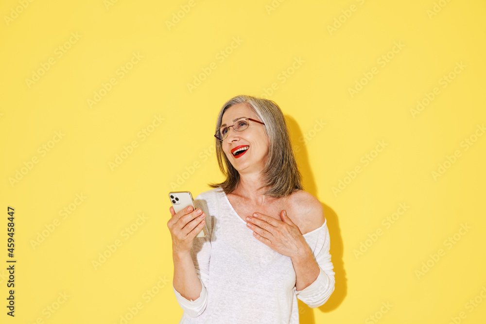 Mature woman in eyeglasses laughing while using mobile phone Mature woman in eyeglasses laughing while using mobile phone