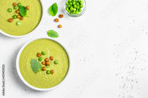 Summer creamy green pea soup in bowls. Top view, space for text, flat lay.