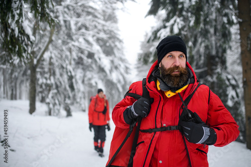 Paramedic man from mountain rescue service with walkie talkie outdoors in winter in forest.