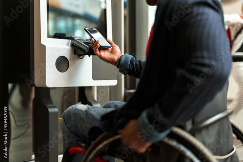 Woman in hijab using mobile phone while buying ticket at station