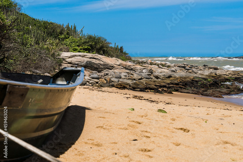 View of the Joana beach in Rio das Ostras in Rio de Janeiro. Sunny day, blue sky. Strong sea and yellowish sand and lots of rocks.