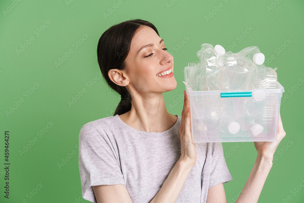 Young brunette woman smiling while posing with plastic waste Young brunette woman smiling while posing with plastic waste