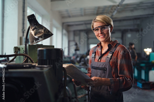 Portrait of mid adult industrial woman working indoors in metal workshop, looking at camera.