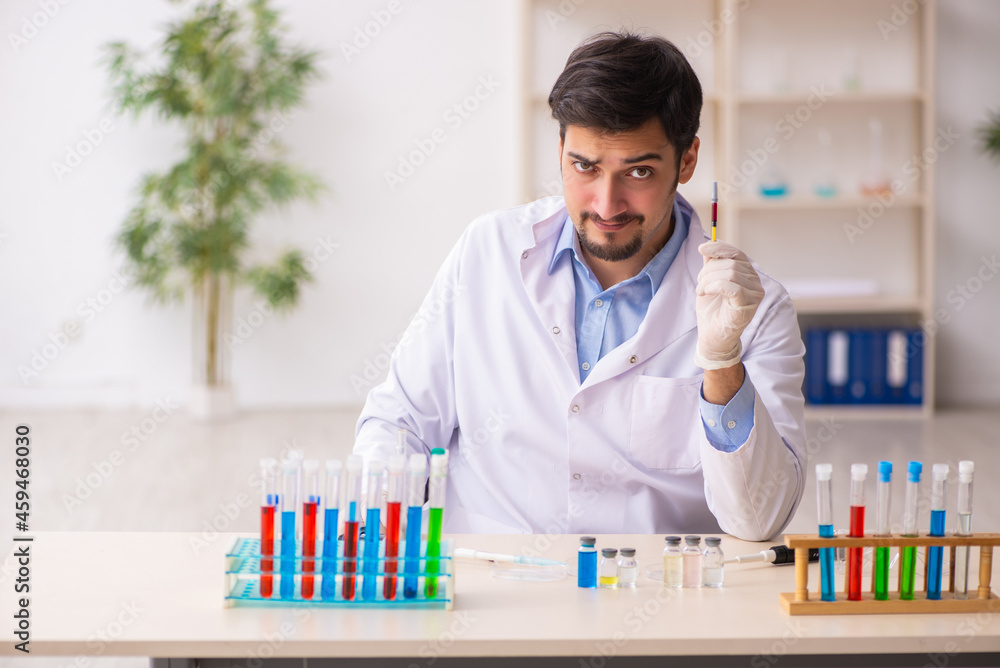 Young male chemist working at the lab in vaccination concept Young male chemist working at the lab in vaccination concept