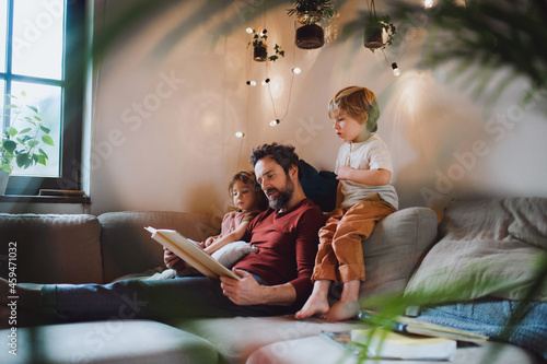 Mature father with two small children resting indoors at home, looking at photo album. photo