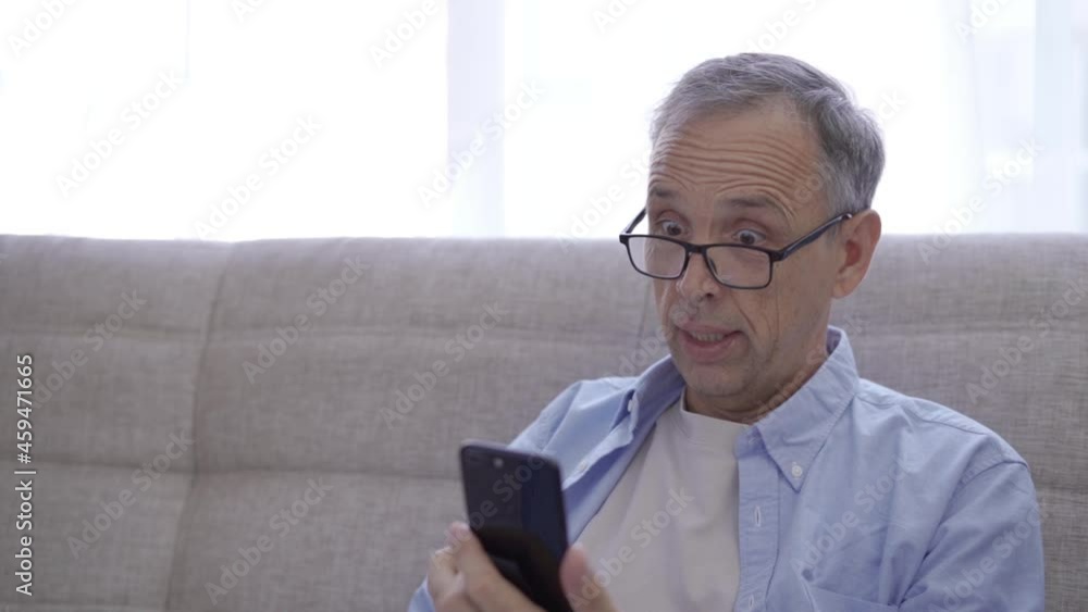 Pensioner rejoices in winning while looking at smartphone screen Pensioner rejoices in winning while looking at smartphone screen