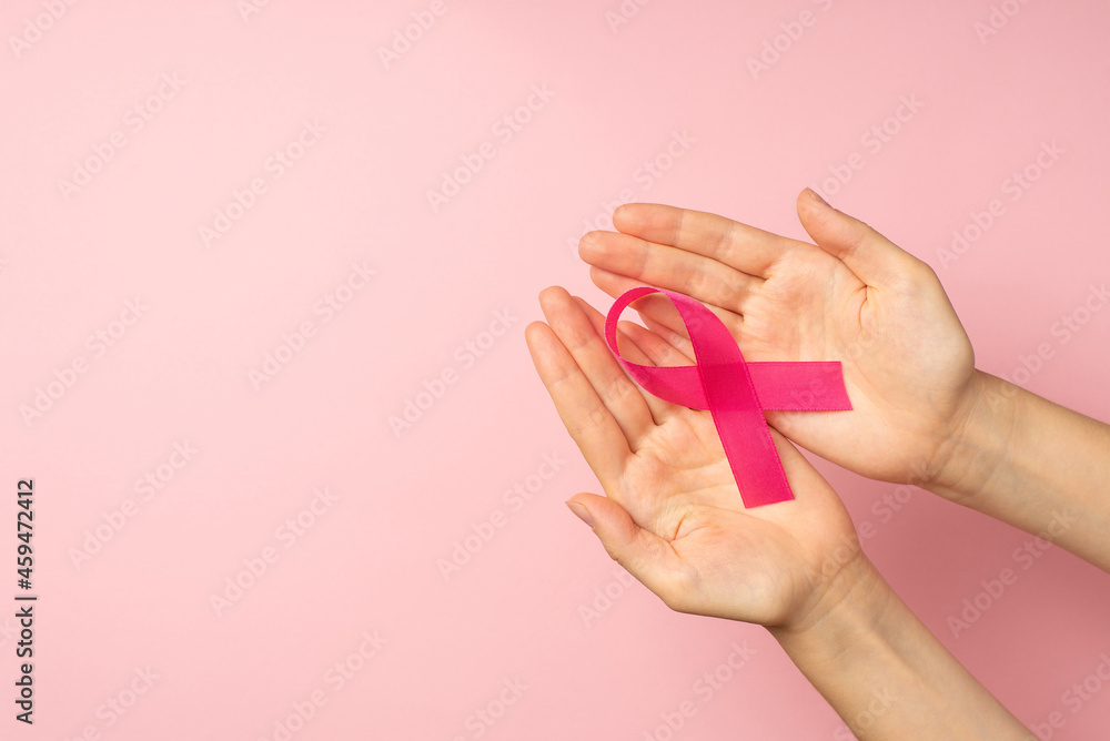 First person top view photo of hands holding pink satin ribbon in palms symbol of breast cancer awareness on isolated pastel pink background with copyspace - obrazy, fototapety, plakaty 