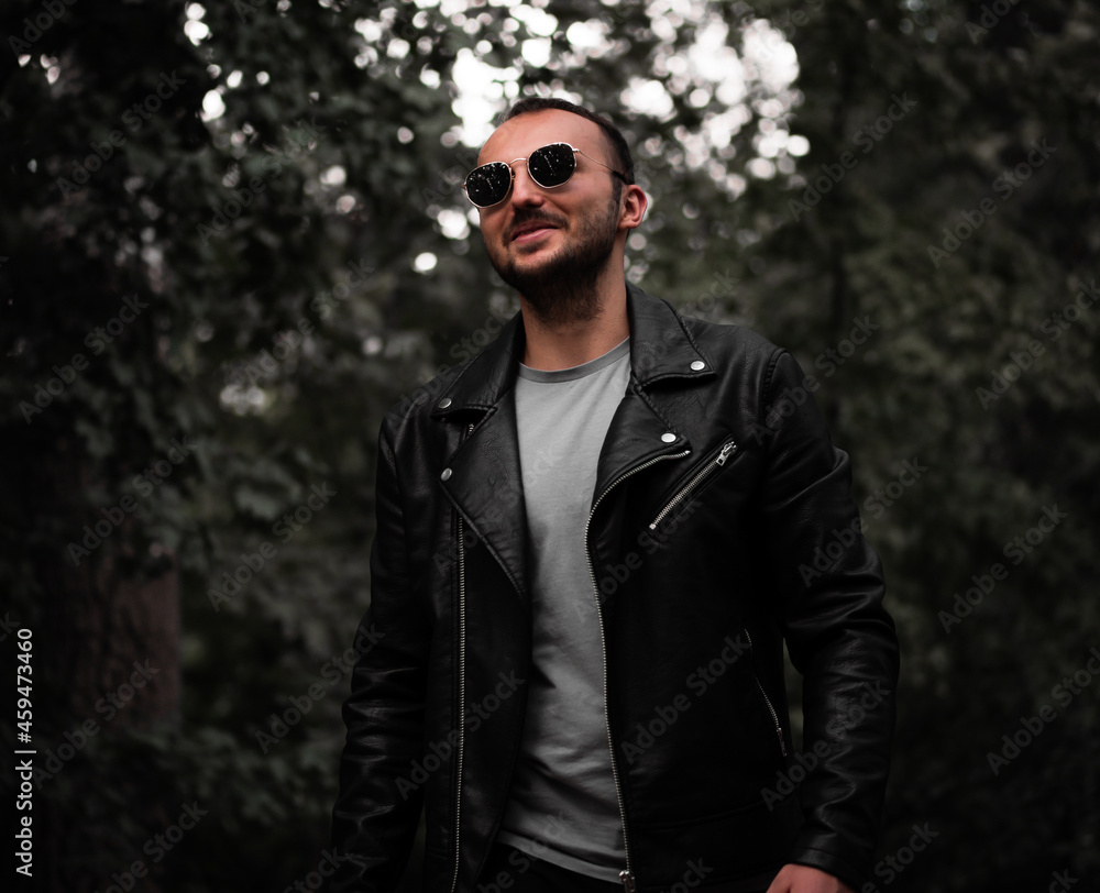 А man with a beard and sunglasses smiling on the background of the forest А man with a beard and sunglasses smiling on the background of the forest