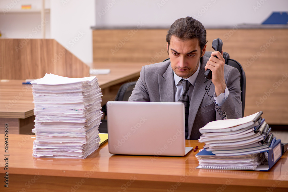 Young male employee and too much work in the office Young male employee and too much work in the office