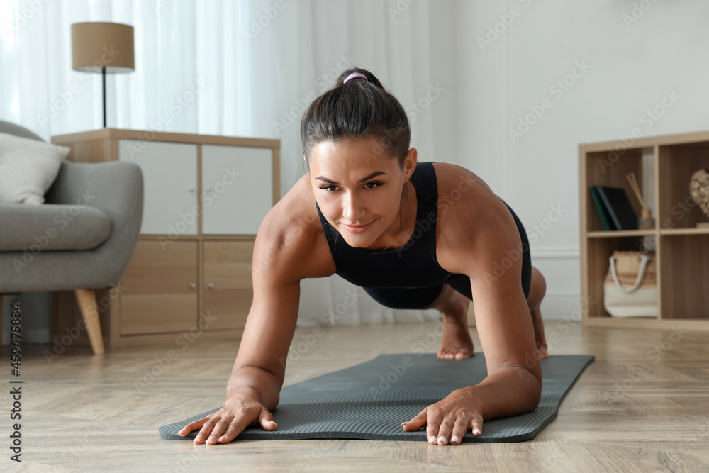 Young woman doing plank exercise on floor indoors Young woman doing plank exercise on floor indoors