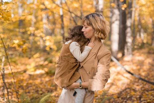 Beautiful lifestyle autumn photo mother and child walks evening in the park, warm sunlight.