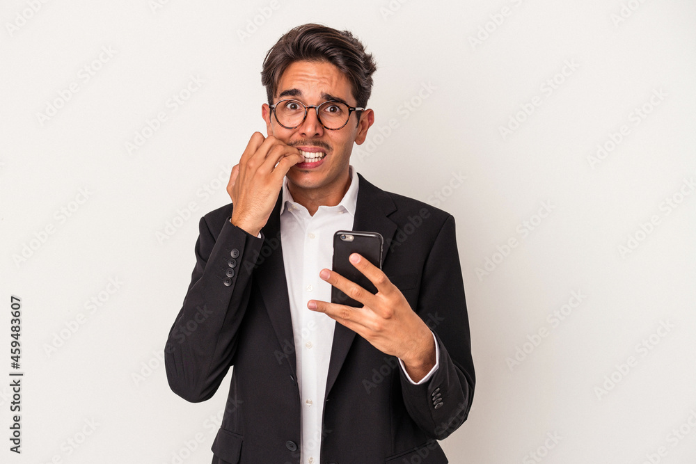 Young mixed race business man holding mobile phone isolated on white background biting fingernails, nervous and very anxious. Young mixed race business man holding mobile phone isolated on white background biting fingernails, nervous and very anxious.