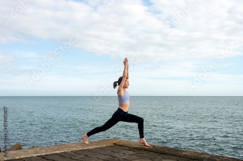 Attractive sporty woman practicing yoga by the sea.