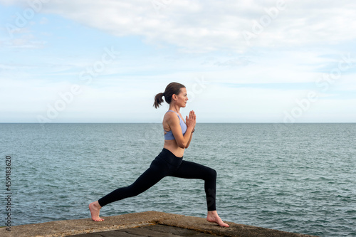 Attractive sporty woman practicing yoga by the sea.