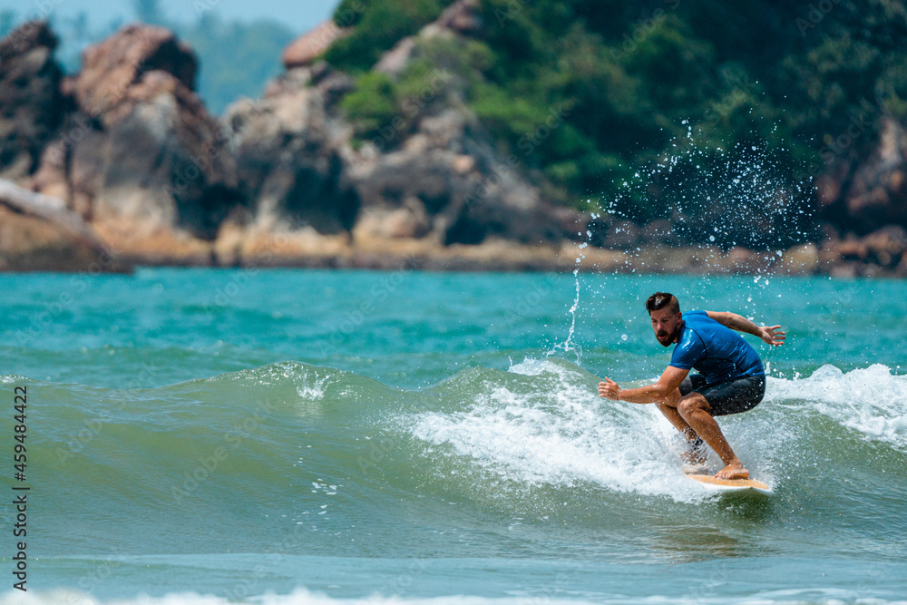 Mężczyzna surfer płynący na fali na tle błękitnego oceanu i nieba.