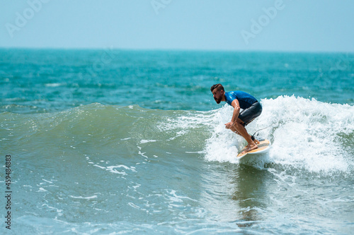 Mężczyzna surfer płynący na fali na tle błękitnego oceanu i nieba. © insomniafoto