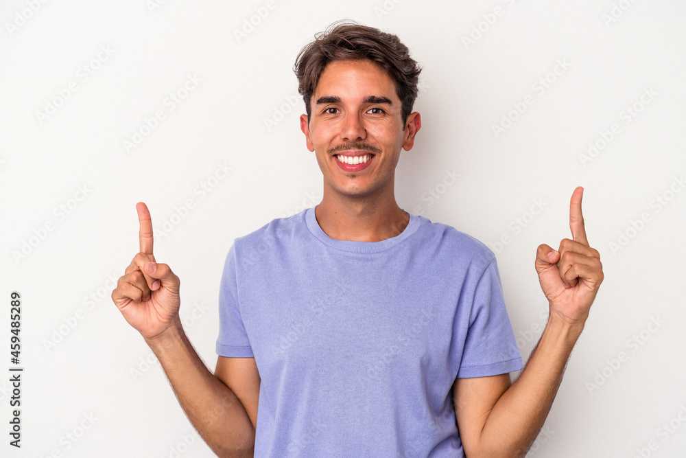 Young mixed race man isolated on white background indicates with both fore fingers up showing a blank space. Young mixed race man isolated on white background indicates with both fore fingers up showing a blank space.