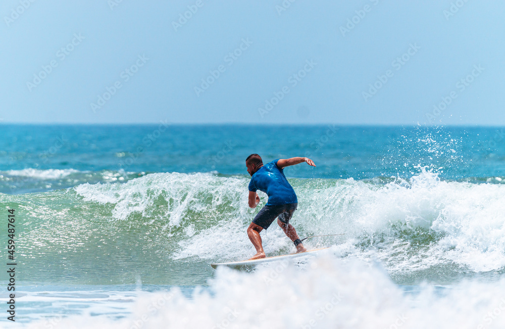 Mężczyzna surfer płynący na fali na tle błękitnego oceanu i nieba.